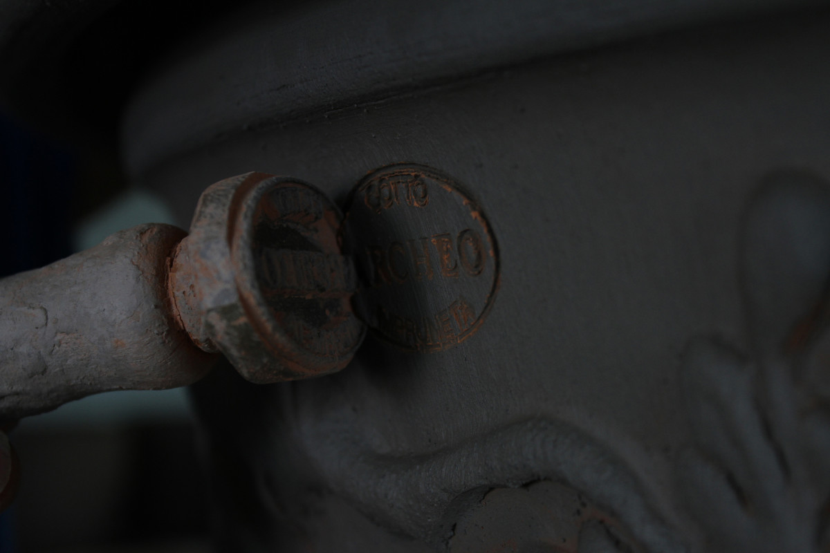 Company name Archeo stamped into wet clay of pot with the stamp face visible